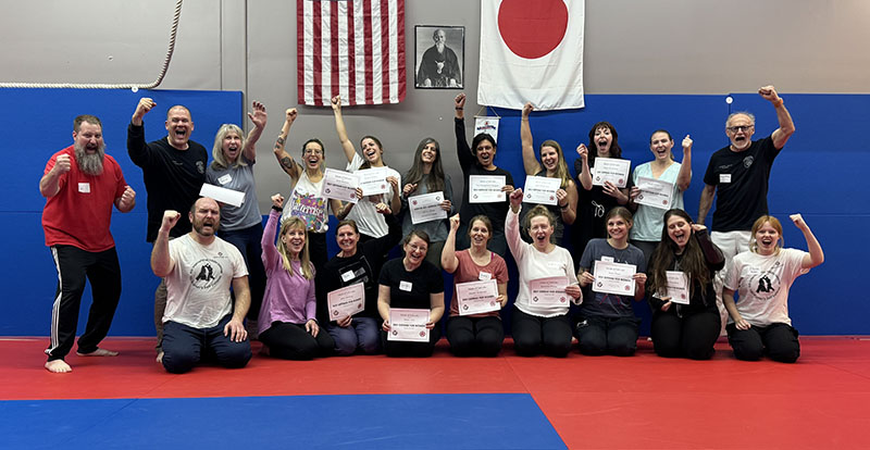 group of women at a self-defense workshop shouting with enthusiasm.